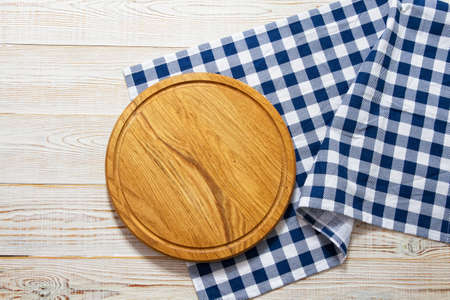 Empty wooden platter with napkin on white table, top view, copy space. Wooden cutting board over...
