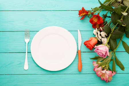 Festive dinner and roses on blue wooden background. Top view. Mock up. Flowers