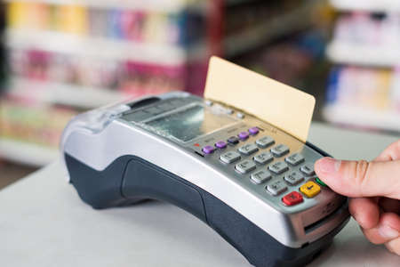Hand press with swiping credit card on payment terminal in supermarketの写真素材
