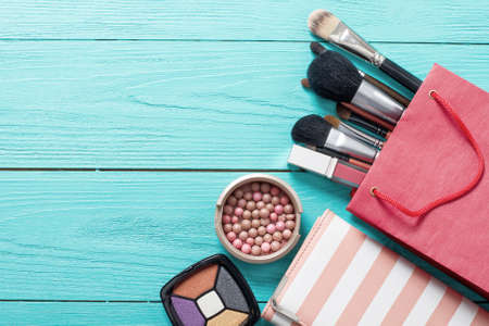 Frame of makeup products and accessories with red bag on blue wooden background. Top view and mock up.の写真素材