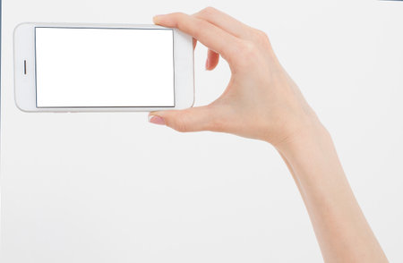 Hand holding white phone isolated on white clipping path inside. Top view.Mock up.Copy space.Template.Blank.の写真素材