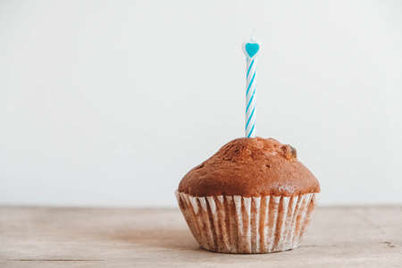 Chocolate cupcake with candle on wooden table. Copy, empty space for text.の写真素材