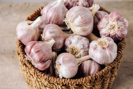 Garlic in a wicker basket on a wooden table background. Copy, empty space for text.