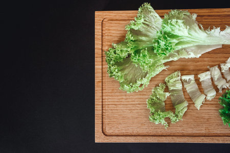 Halves of fresh cabbage on old brown wooden table on black background with copy space. Top view.