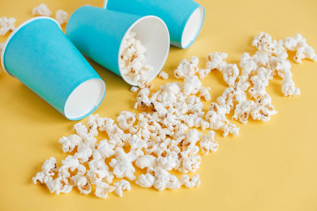 Popcorn in blue paper cups on a yellow background. Top view. Copy, empty space for text.の写真素材