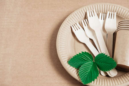 Wooden forks and paper cups with plates on kraft paper background. Eco friendly disposable tableware. Also used in fast food, restaurants, takeaways, picnics. Top view. Copy, empty space for text.の写真素材