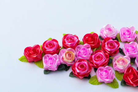 Many artificial roses background from beautiful pink and red ribbons placed on a white background.