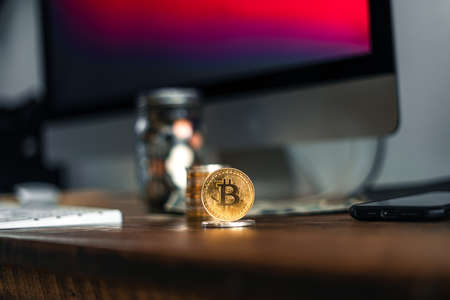 Golden bitcoins placed on a wooden desk in the house.の写真素材