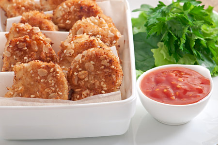 Chicken nuggets coated in cereals, crumbs and sesame