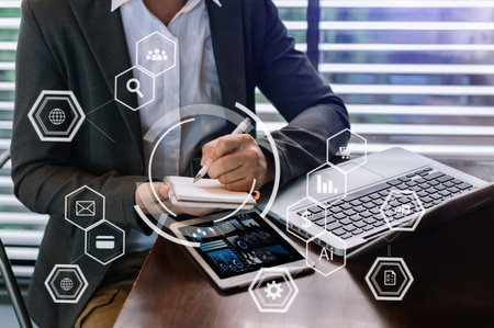 Businesswoman hand working digital marketing media in virtual screen with mobile phone and modern compute with VR icon diagram at office in morning lightの写真素材