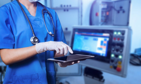 Female Doctor Wearing Scrubs In Hospital Using Digital Tablet with cinematography screen.Smart...