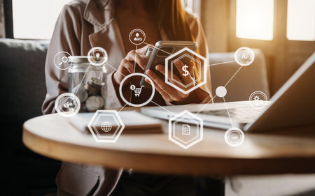 Businesswoman hand working digital marketing media in virtual screen with mobile phone and modern compute with VR icon diagram at office in morning lightの写真素材