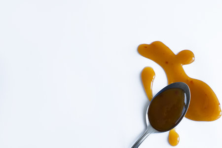 drops of homemade sauce and a spoon on a white backgroundの写真素材