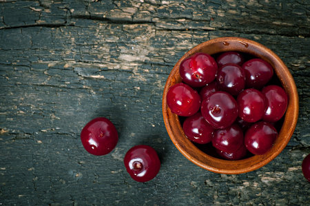Ripe cherries in ceramic bowl on wooden backgroundの写真素材