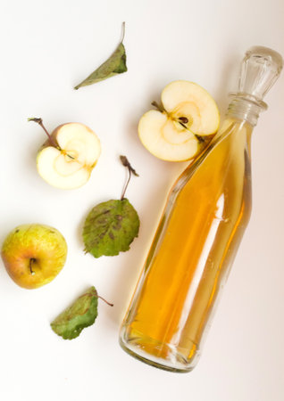 Top view, a bottle of apple cider vinegar and apple fruit composition with leaves on white background.の写真素材