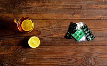 A hot drink for a cold. Autumn. disease. Health. A Cup of Tea with two pieces of lemon and cold pillsの写真素材