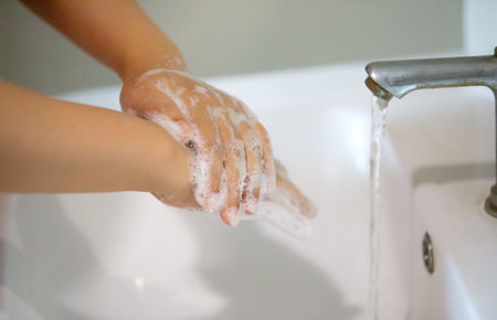 women washing hand with foam soap in bathroom sink.の写真素材