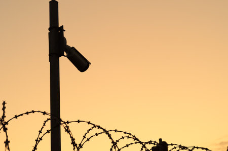 Silhouette of the Security camera on the pole on sunset.Observation of the perimeter of the...