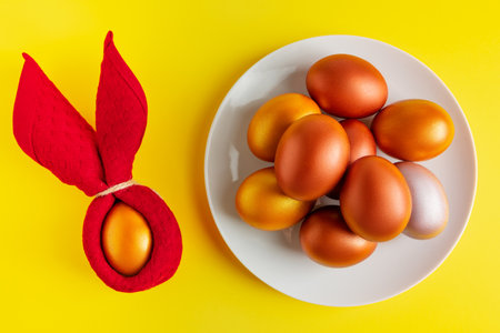 Gold glittering Easter eggs on yellow background. Happy spring holiday.
