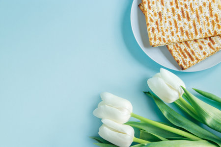 Happy Passover concept. Matzo and white tulips on blue background. Religious Jewish holiday Pesach. Copy space, flat lay.の写真素材