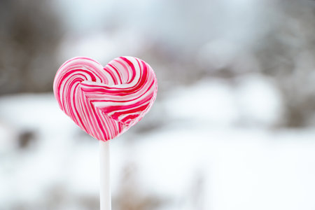 Heart shaped pink lollipop. Caramel candy on a stick. Sweet gift for valentines day.の写真素材