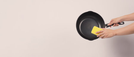 Cleaning Electric non stick pan. Hand on white background cleaning the non stick pan with handy dish...