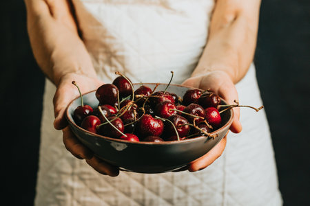 Old waitress offers and holds a bunch of cherry in a bowl, fruits, healthy life, good eating,...