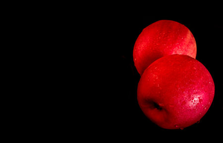 Close-up of Water droplet on glossy surface of freshness red apple on black background