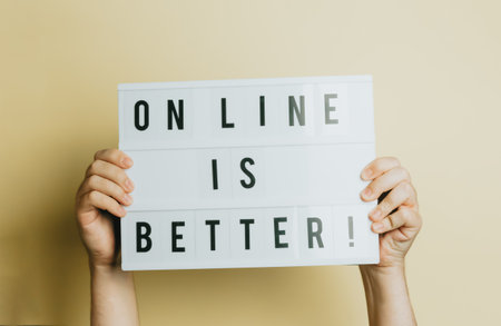 Two hands holding a sign that says online is better over a pastel yellow background, styling and design concept, copy space, buy online and e-commerceの写真素材