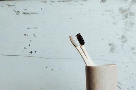 A pair of bamboo toothbrushes over a white wooden background inside a bamboo bottle with copy spaceの写真素材
