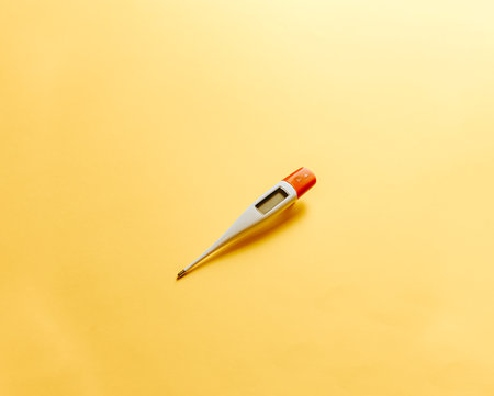 A thermometer over a flat and minimal yellow background with copy spaceの写真素材
