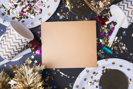 Blank golden greeting card with party cup,party blower,tinsel,confetti.Holiday celebrate party time table top view mock upの写真素材