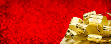 Golden gift box with big bow at red bokeh white blur background, Leave space for adding your...