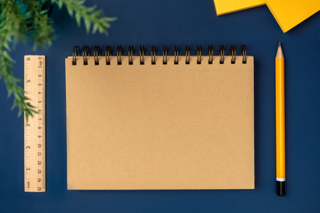 top view brown notebook with yellow pencil and notepad on navy blue working table