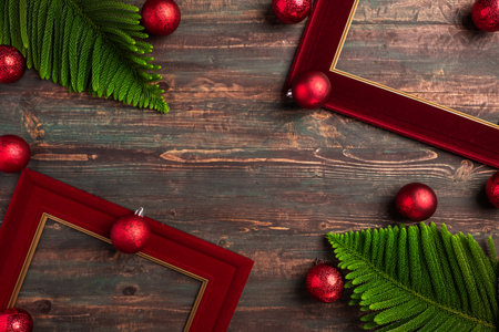 Christmas red picture frame with pine leaf and bauble decor on wood tableの写真素材