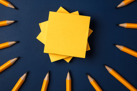 blank yellow sticky note and pencil on navy blue table background