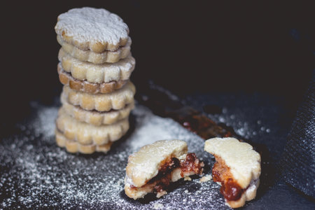 Stack of homemade vanilla jam cookies, on dark background, with copy space
