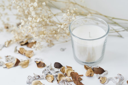 Candles with floral decor on white table. Cozy and hygge backgroundの写真素材