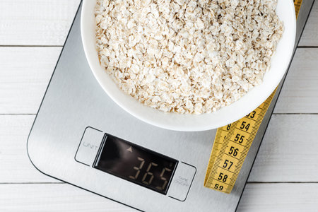 Diet concept, proper nutrition, healthy eating. Oatmeal in a white plate on the kitchen scale. Top...