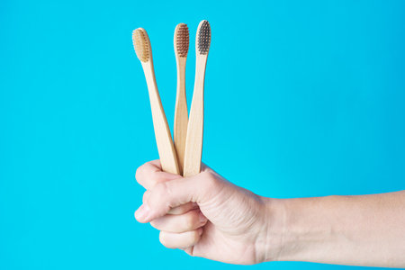 Three wooden eco friendly bamboo toothbrushes on blue background. Dental care conept
