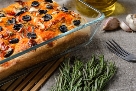 Traditional Italian vegetarian focaccia of homemade bread with olives, rosemary and garlic on a close-up background.の写真素材