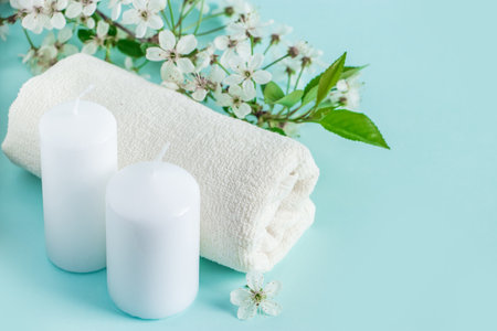 Aromatherapy wellness concept. Spa and relaxation accessories on a blue background. Aromatic oil, towel, candle and flowers. Organic skin care product.の写真素材