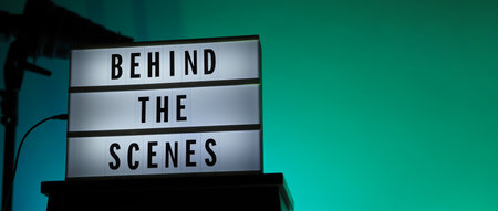 Behind the scenes text on Lightbox or Cinema Light box. Movie board light box on studio stair and light Snoot tripod on colors gradiant Background. Represent behind the scenes team is working on.の写真素材
