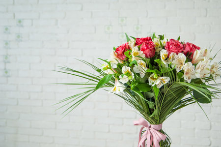 A beautiful bouquet with roses and white alstroemeria against a white wallの写真素材