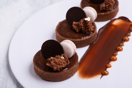 A closeup shot of a delicious chocolate dessert with macaroon served on a white plateの写真素材