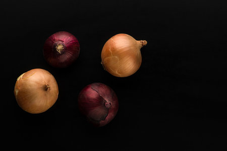 raw and unpeeled onion in red and golden colors on black background top viewの写真素材