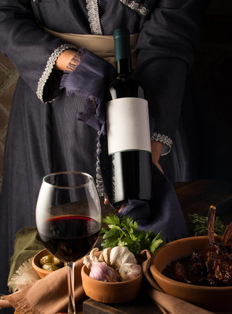 A vertical shot of a person in a traditional costume showing a wine bottleの写真素材