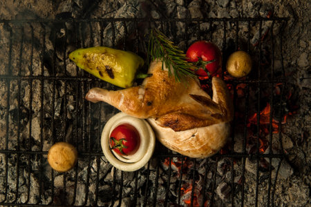 chicken meat with vegetables on a metal grill lay on charcoal. the dish is cooked and smoked on charcoalの写真素材
