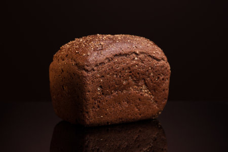 one loaf of bread close-up on a dark background with reflection