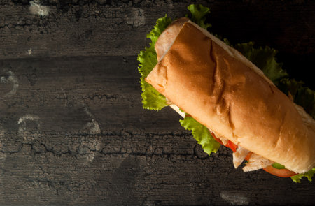 cheeseburger on an old wooden surface of dark color. hamburger with chicken meat on an old wooden...